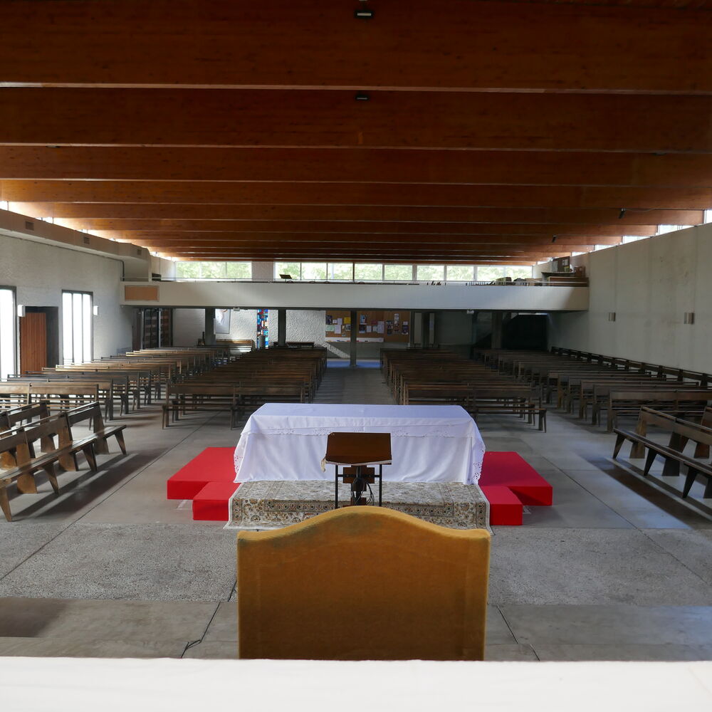 Vue d'ensemble de la nef avec le maître-autel et les bancs.