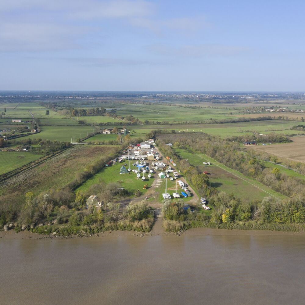 Cette image aérienne présente les eaux boueuses de la Garonne au premier plan. Au-delà, un chantier 
