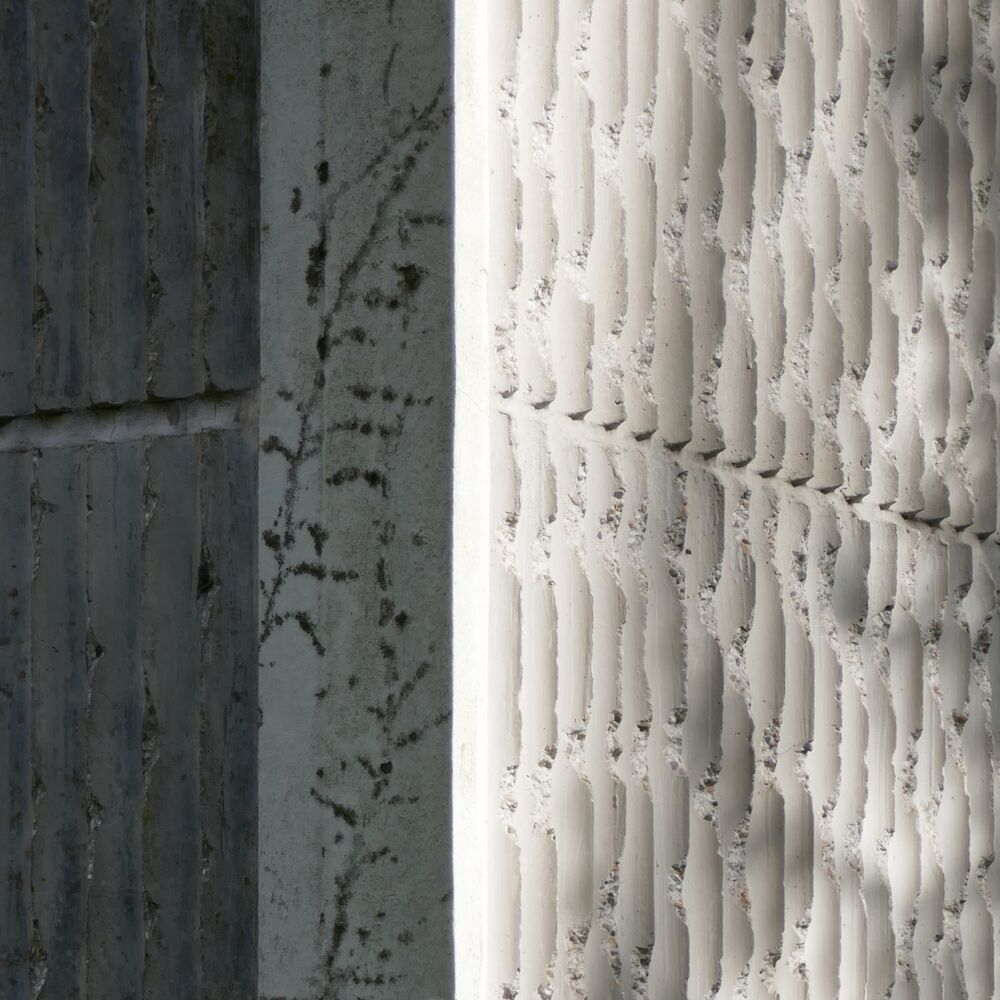 Détail des angles revêtus de plaques de béton blanc cannelé.