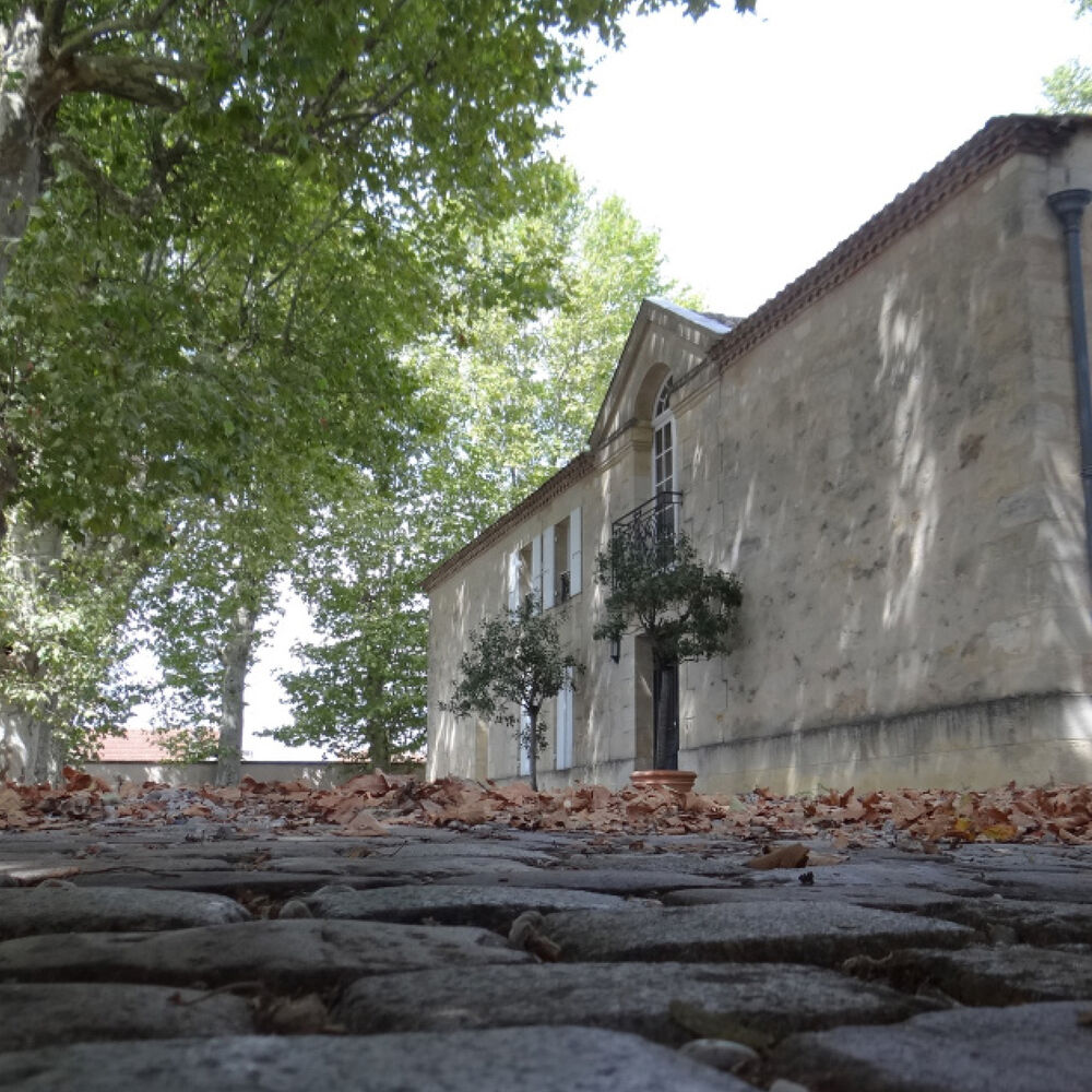 Vue sur la cour pavée et la façade principale de la maison
