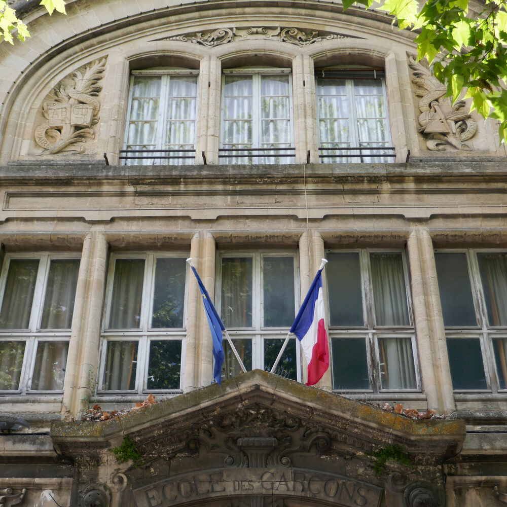 L'entrée de l'école des garçons surmonté d'un fronton orné de tables de l'alphabet et des sciences.