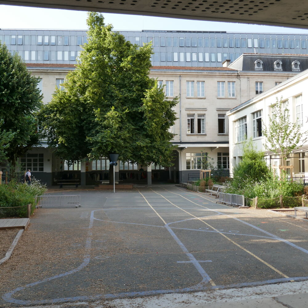 La cour du groupe scolaire avec, au fond, la cité municipale.