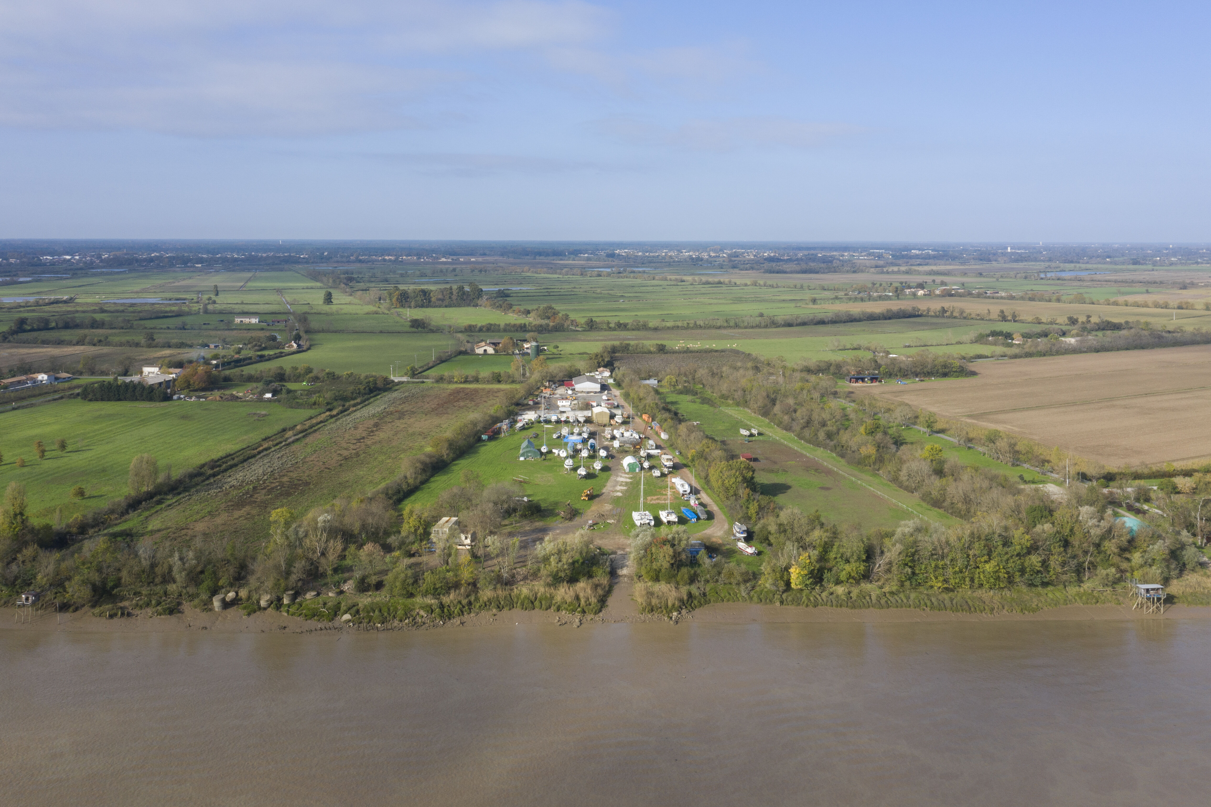 Cette image aérienne présente les eaux boueuses de la Garonne au premier plan. Au-delà, un chantier 