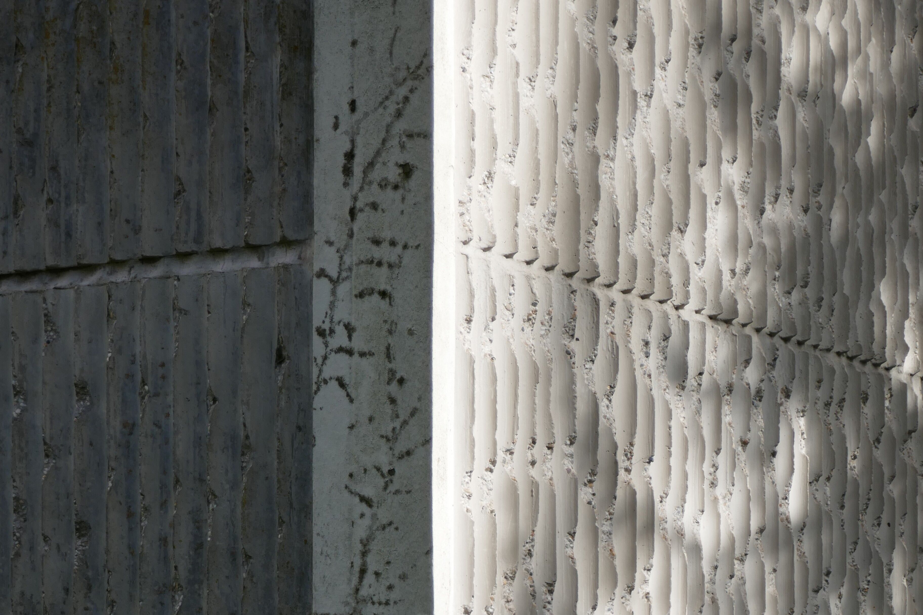 Détail des angles revêtus de plaques de béton blanc cannelé.