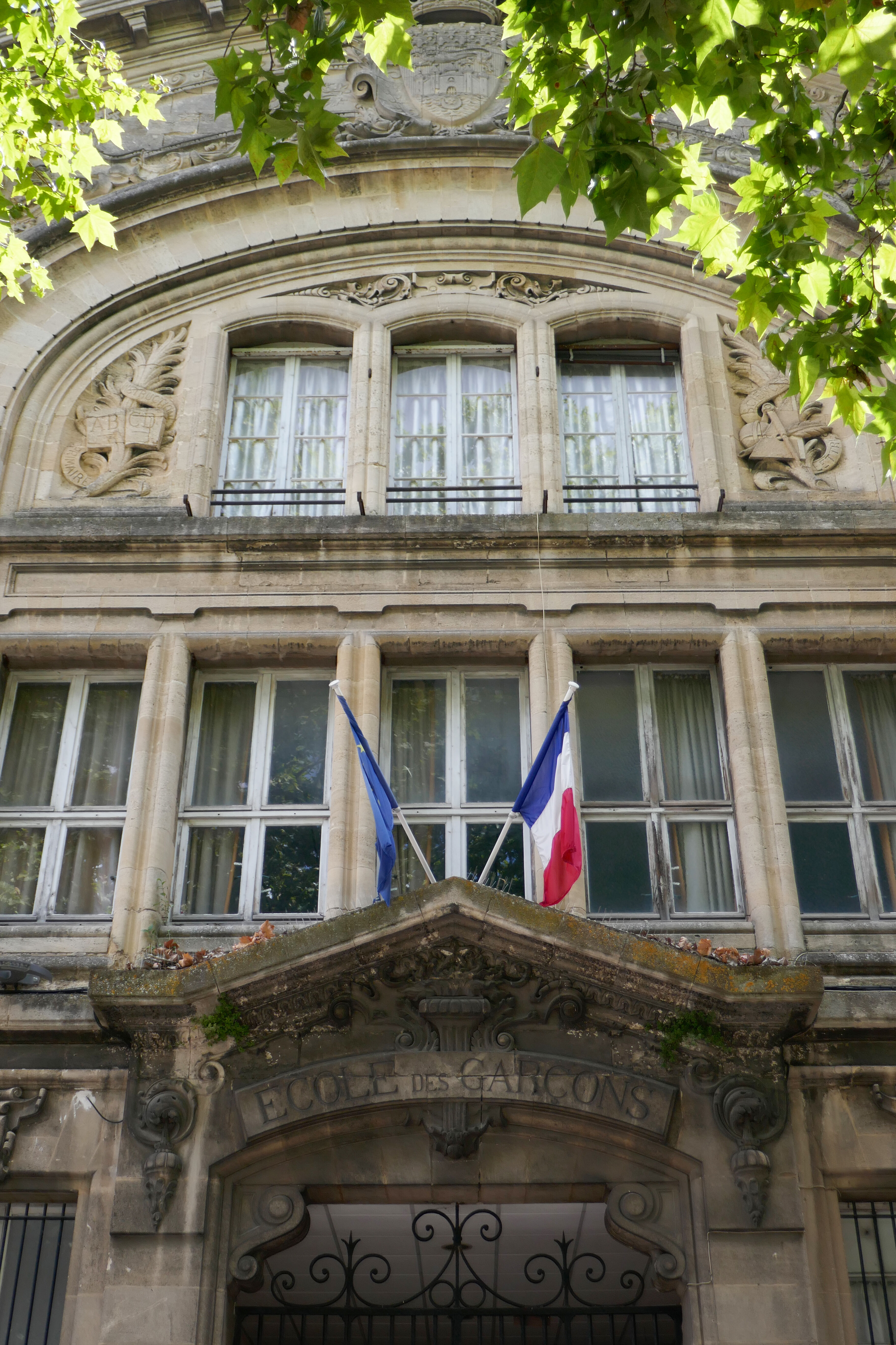 L'entrée de l'école des garçons surmonté d'un fronton orné de tables de l'alphabet et des sciences.